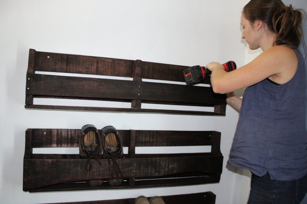 attaching the wood pallet shoe racks to the wall