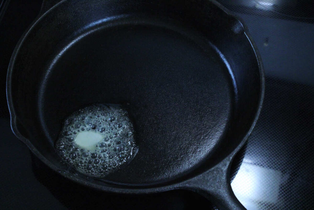 butter melting on a cast iron pan over a stovetop