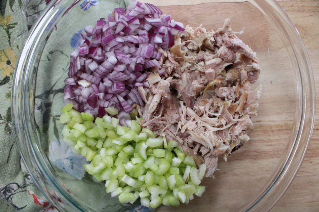 a bowl of shredded chicken or rabbit, sliced celery and diced red onion