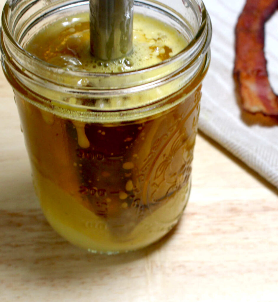 mixing together ingredients for bacon mayonnaise in a mason jar with an immersion blender