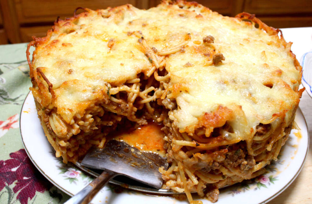 baked spaghetti pie on a plate with a piece cut out from it