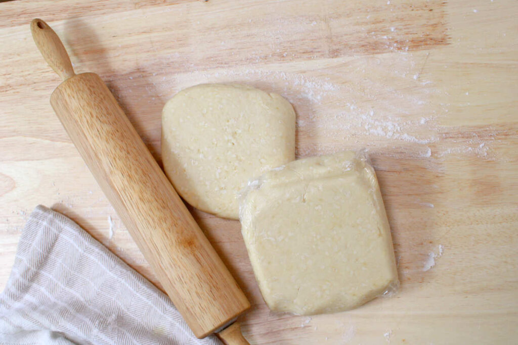 two pie crusts on a counter with flour and a rolling pin