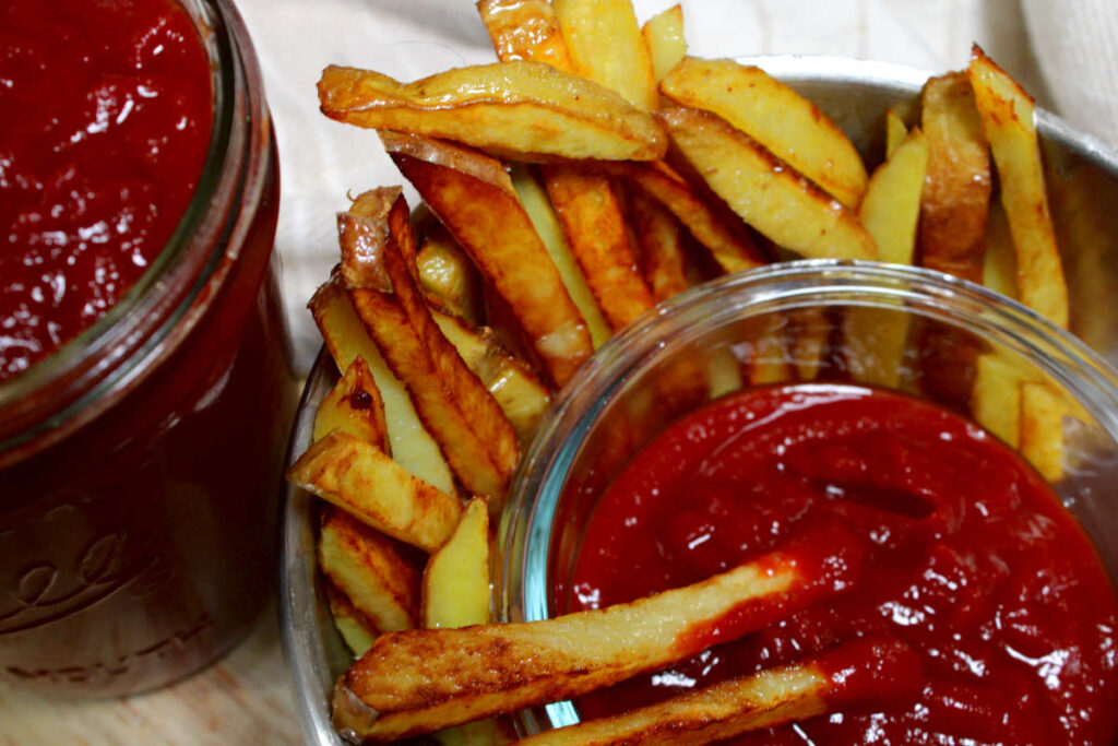 a bowl of ketchup with fries and a jar of homemade ketchup