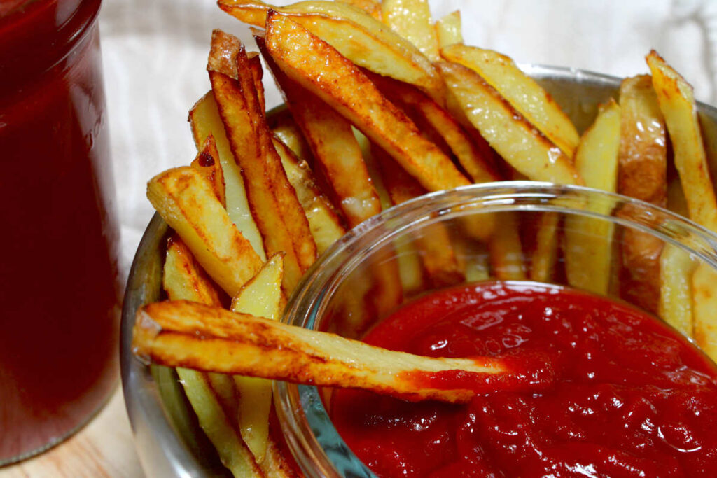 a bowl of sugar free ketchup and dipping French fries in it